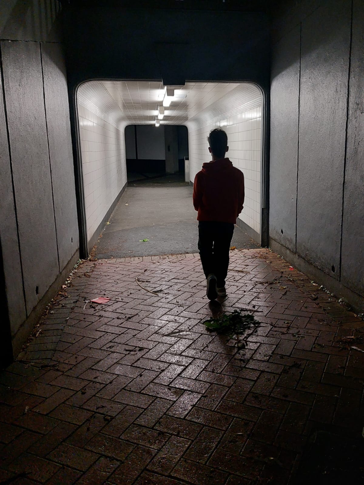 A person walking through a tunnel at night.